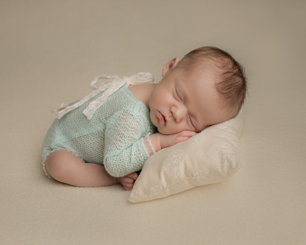 Newborn baby gril dressed in little green romper with lace